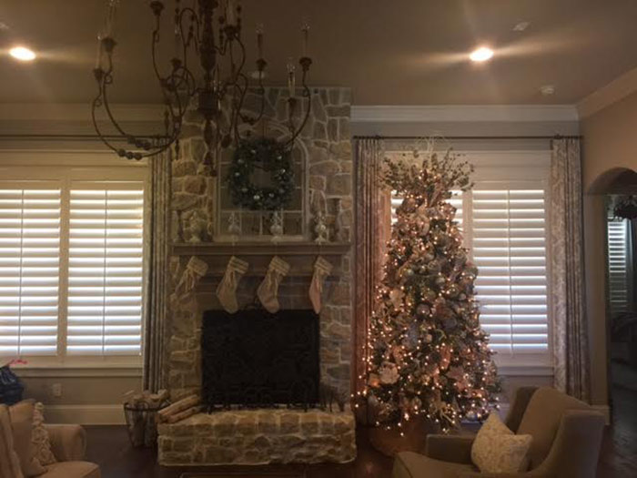 Blinders behind a well decorated Christmas tree and fireplace with stalkings